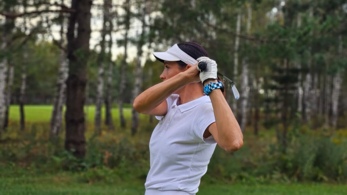 woman swinging a golf club from a side view
